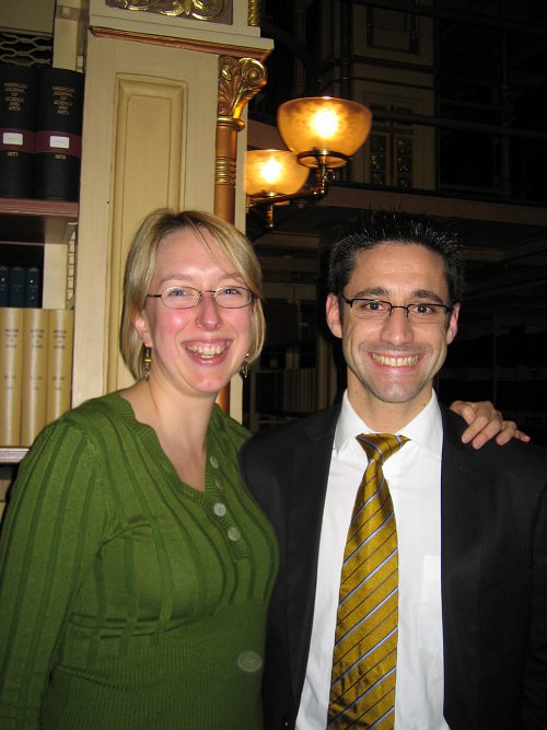 Photograph showing a blond woman in a green dress and dark-haired man in a suit and tie. Both are smiling